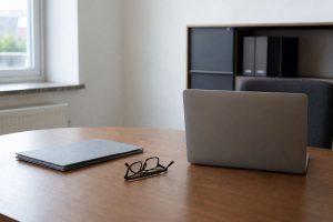 Schreibtisch mit Aktenordner und Lesebrille